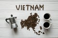 Map of the Vietnam made of roasted coffee beans laying on white wooden textured background with coffee maker and cups of coffee Royalty Free Stock Photo