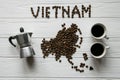 Map of the Vietnam made of roasted coffee beans laying on white wooden textured background with coffee maker and cups of coffee Royalty Free Stock Photo