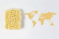 Map of the world made of raw pasta on brown fabric background with texture with white ceramic bowl full of pasta Royalty Free Stock Photo