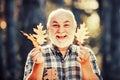 Maple leaf on hiking trail in park. Happy senior man looking at camera. Autumn portrait of grandfather. Elderly old man Royalty Free Stock Photo