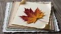 Maple leaf lies on a stack of textured, deckle-edged paper in Royalty Free Stock Photo