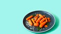 Maple-Roasted Carrots in plate on green background. Creative copy space