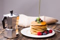 Maple syrup pouring over a stack of mini pancakes.