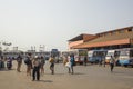 Indian people and tourists walk at the bus station amid parked colorful buses and buildings