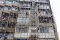 Workers on construction site building bamboo scaffolding on house facade in Hong Kong