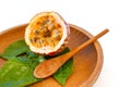 Maracuja cut in half and whole in small glass container peel of the fruit with wooden spoon and leaf on plate and white background