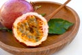 Maracuja cut in half and whole in small glass container peel of the fruit with wooden spoon and leaf on plate and white background