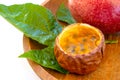 Maracuja cut in half and whole in small glass container peel of the fruit with wooden spoon and leaf on plate and white background