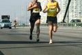 Marathon running race, people feet on city road. Two young runners a few meters from the arrival of the difficult marathon through