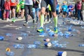 Marathon running race, runners feet and plastic water cups on road near refreshment point, sport