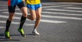 Marathon running race, two men runners on city roads, detail on legs