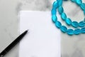 Marble background. Markers blue and a sheet of paper. Sheet for notes, blue theme. Notes of girls and blue beads