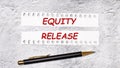 On a marble background are two torn strips of white paper with the text EQUITY RELEASE and a black pen Royalty Free Stock Photo