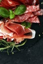 Marble cutting board with prosciutto, bacon, salami and sausages on wooden background. Rustic Meat platter