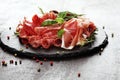 Marble cutting board with prosciutto, bacon, salami and sausages on wooden background. Rustic Meat platter