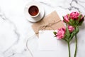 Marble desk with cup of coffee, pink flowers, postcard, kraft envelope, twine, cotton branch, oat cookies, invitation card Royalty Free Stock Photo