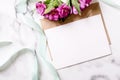 Marble desk with pink flowers, postcard, kraft envelope, twine, cotton branch, invitation card with copy space for your text. Royalty Free Stock Photo