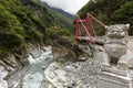 Marble lion statue in front of a red Cimu Bridge at Taroko