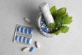 Marble mortar with fresh green herbs and pills on white table, flat lay Royalty Free Stock Photo