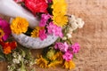 Marble mortar, pestle and different flowers on wooden table, closeup Royalty Free Stock Photo