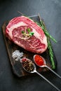 Marble raw Ribeye Steak with seasonings and red pepper on cutting Board on grey background