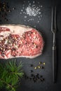 Marble ribeye steak, juniper, larch branch and fork on blue-black slate