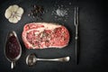 Marble ribeye steak, pepper, garlic, spoon, fork on blue-black s