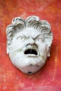 Marble sculpture of an angry face Roman or Greek against a red wall Royalty Free Stock Photo