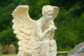 Marble sculpture of female angel sitting on the rock and holding a bird in her hands