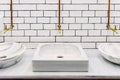 Marble sink in a public restroom with retro golden water tap with copper pipes on wall with white tiles, front view with room for Royalty Free Stock Photo