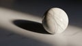 Marble sphere with gray veining rests on a smooth surface casting a soft Royalty Free Stock Photo