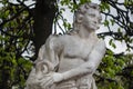 Marble statue of classical male figure in green leafy park setting Royalty Free Stock Photo