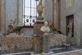 A marble statue of a Pope flanked by two statues of peacocks in one of the museums in Vatican City, Rome