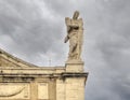 Marble statue of a saint on the top right edge of the Basilica of Saint Mary of the Angels in Assisi, Italy.