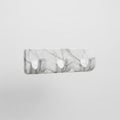 A marble-textured modern triple hook, floating in mid air horizontally on a solid white background Royalty Free Stock Photo