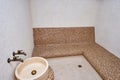 Marble washbasin with two taps opposite the mosaic sofa in the hammam