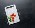 Marble white cutting board ripe spice cherry tomatoes black background. Ingredients fresh vegetables Royalty Free Stock Photo