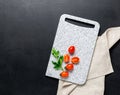 Marble white cutting board ripe spice cherry tomatoes black background. Ingredients fresh vegetables Royalty Free Stock Photo