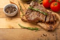 Marbled beef steak on a board with rosemary pepper, spices, and fresh vegetables, tomatoes and asparagus, artichoke, on a wooden Royalty Free Stock Photo