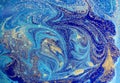 Marbled blue abstract background with golden sequins. Liquid marble ink pattern.