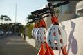 Four orange and black Neuron rent to ride electric scooters with white protective helmets on a pavement sidewalk beside Auckland H