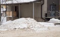 March big snowdrift by the road against the backdrop of city houses. Royalty Free Stock Photo