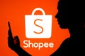 March 22, 2022, Brazil. In this photo illustration, a woman`s silhouette is holding a smartphone with an Shopee logo in the