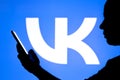 March 23, 2022, Brazil. In this photo illustration, a woman`s silhouette holds a smartphone with a VKontakte VK logo in the