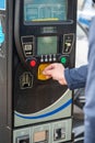 28 March, 2023. Corby, United kingdom. A man's hand putting coins in a parking meter, to pay for parking.