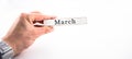 March - A hand holding calendar month block on white background Royalty Free Stock Photo