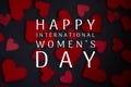 Happy International Women`s Day lettering with white text on black background with red heart