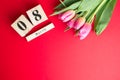 8 March Happy Women`s Day concept. With wooden block calendar and pink tulips on red background. Copy space