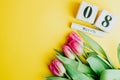 8 March Happy Women`s Day concept. With wooden block calendar and pink tulips on yellow background. Copy space