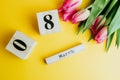 8 March Happy Women`s Day concept. With wooden block calendar and pink tulips on yellow background. Copy space Royalty Free Stock Photo